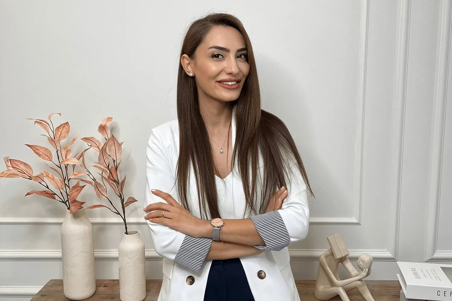 Uzm. Dr. Hazal Tonya, klinikte kollarını kavuşturmuş gülümsüyor